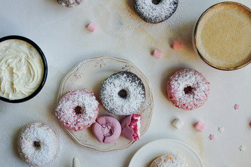 Strawberry and lavender macarons, sweet donuts with cup of capuccino and marshmallow on white marble table