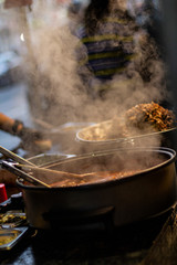 Street food, barbecuing on a hot grill with fire and smoke, thai food, vegetables and meat cooked for taking out. Brick Lane Food Market