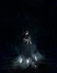 Man crouching on a large tree stump, discovering the mystic light coming from within