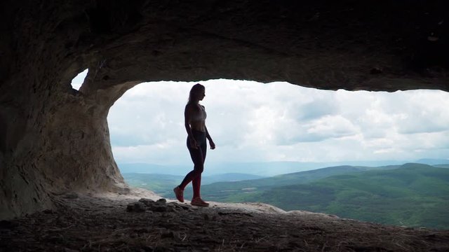 Girl traveler walks through the cavern. Cave city in the vicinity of Bakhchisarai - tope kermen. Attractions in Crimea. Slow motion. Shooting on the Steadicam