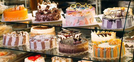 Pastry shop glass display with selection of cream or fruit cake.