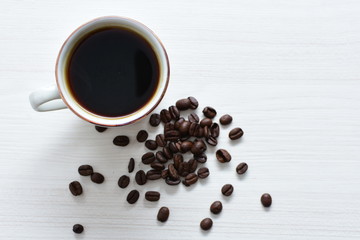 Traditional cup of Colombian coffee with coffee beans on wooden background