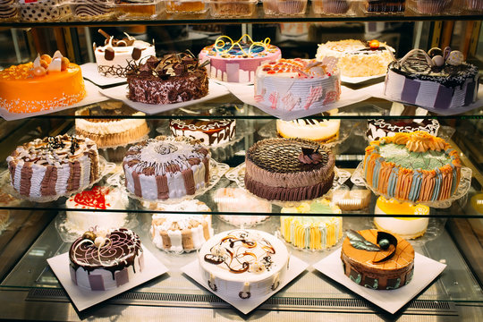 Pastry shop glass display with selection of cream or fruit cake.