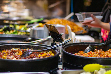 Street food, barbecuing on a hot grill with fire and smoke, thai food, vegetables and meat cooked for taking out. Brick Lane Food Market