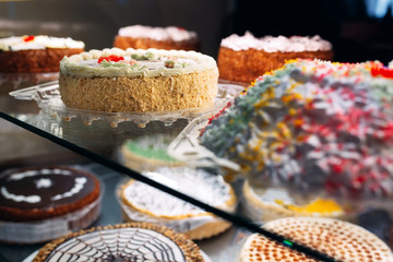 Pastry shop glass display with selection of cream or fruit cake.