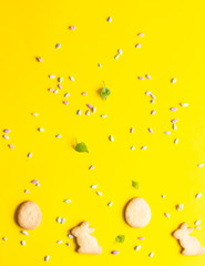 Easter cookies with multi-colored sprinkles on yellow paper background. Easter symbols and traditions. Butter and sugar cookies.