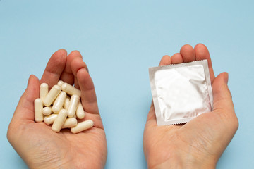 Woman holding birth control pills and condom in hand. Birth control pills prevent pregnancy or...