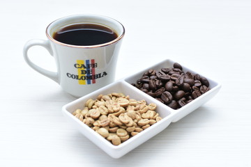 Traditional cup of Colombian coffee with coffee beans on wooden background