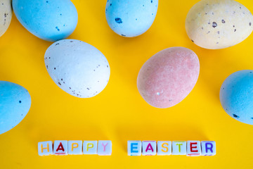 Easter greeting card with painted eggs. Seasonal Easter message  "Happy easter". Pastel and colorful   decorated easter eggs with greeting card with text on yellow background. Spring holidays concept.