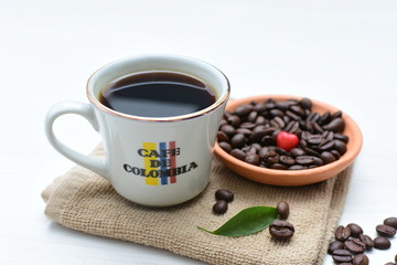 Obraz na płótnie Canvas Traditional cup of Colombian coffee with coffee beans on wooden background