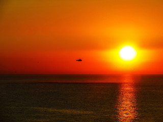 Helicopter over the sea at sunset