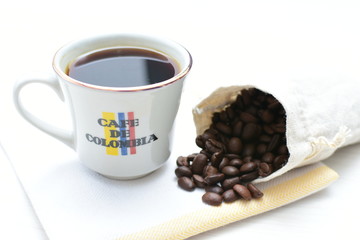 Traditional cup of Colombian coffee with coffee beans on wooden background