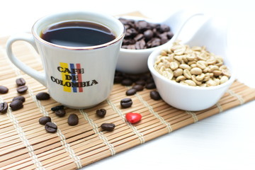 Traditional cup of Colombian coffee with coffee beans on wooden background