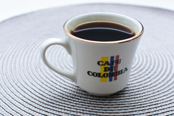 Traditional cup of Colombian coffee with coffee beans on wooden background