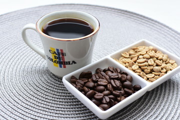 Traditional cup of Colombian coffee with coffee beans on wooden background