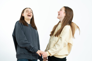 Happy girls in hoodies holding hands together and laughing isolated over white background