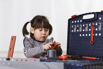 toddler girl pretend using DIY tool at home against white background