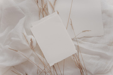 Wedding invitation mockup with paper, dry branches on white textile background. Top view, flat lay. Wedding stationary. Perfect for presentation of your wedding invitation, menu, greeting cards