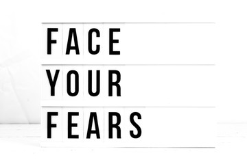 Face Your Fears flat lay on a wooden white background. Motivational business start up board