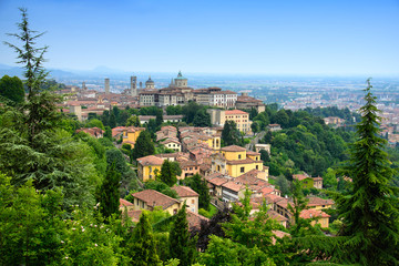 Fototapeta na wymiar Paesaggio urbano di Bergamo con le case antiche dall'alto e le zone erbose ed alberi con contrasto del cielo
