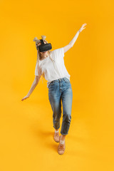 Young blonde woman losing balance while playing virtual reality game with headset glasses