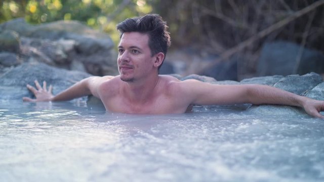 A young caucasian man relaxing in a hot spring on a cold weather.