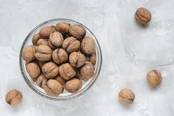 Uncracked walnuts in shell in bowl on gray background, concept of healthy eating vegan food. Close up, selective focus, copy space.