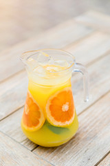 Summer yellow-orange lemonade with ice . Refreshing lemonade with oranges and mint on a wooden table