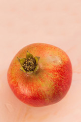 One red ripe pomegranate on a pink background. Selective focus, copy space.
