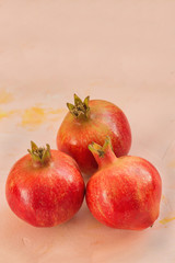 Three red ripe pomegranate on a pink background. Selective focus, copy space.