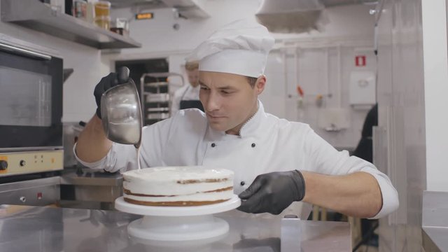 Male pastry chef preparing cake at table in kitchen