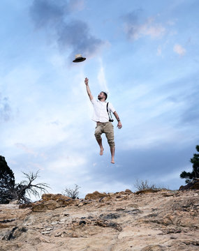 Man jumps after his hat as it flies away, artistic image