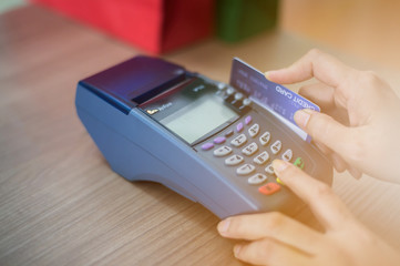 The store staff is swiping a credit card to pay for the product. Concept of payment using a debit card.