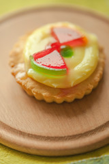 Sweet round cake with yellow cream and red jelly watermelon slices on wooden board.