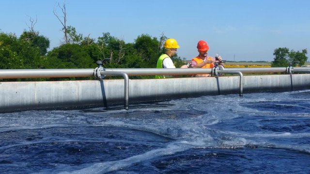 Engineers controlling a quality of water ,aerated activated sludge tank at a waste water treatment plant       