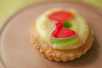 Sweet round cake with yellow cream and red jelly watermelon slices on wooden table.
