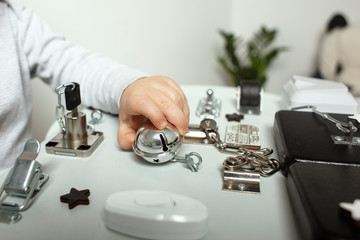  Toddler play with a wooden game board at home. Child play at the table in the baby room. Baby's hands play with DIY sensory board .Detail. Hands playing with a busy board at home.