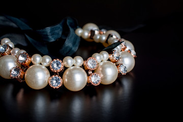Gold black and pearl  jewelry on  dark background.