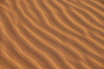 sand texture - background of desert sand dunes. Beautiful structures of sandy dunes. sand with wave from wind in desert - Close up