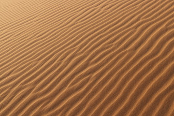 sand texture - background of desert sand dunes. Beautiful structures of sandy dunes. sand with wave from wind in desert - Close up