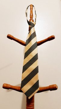 Green and gold tie on a wooden hanger