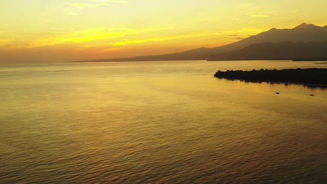 Cinematic golden sunset over the peaceful sea with the island and mountains in the background. Bali, Indonesia, Gilli islands