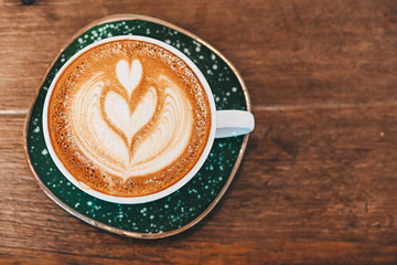 High angle view of a cup of hot latte coffee on the wooden table. A latte is a coffee drink made with espresso and steamed milk.
