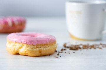 Pinky donut on white table serve with coffee in blur background 