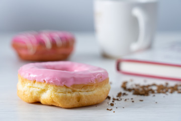 Pinky strawberry donut serve with coffee on white table in the morning