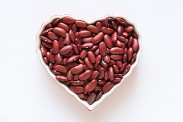 Obraz na płótnie Canvas Uncooked Red Kidney Beans in a Heart Shaped Bowl