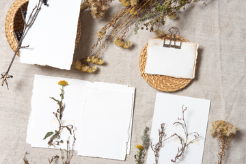 Autumn atmospheric mockup with dry plants , papers on grey textile background. Top view, flat lay. Wedding stationary. Perfect for presentation of your invitation, menu, greeting cards