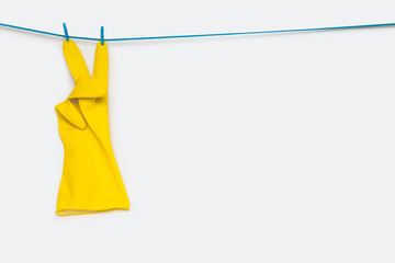 Yellow rubber gloves hanging with a blue clothes pin. victory symbol and letter V on white background.