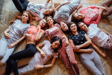 Top view of nine happy beautiful women laying on the floor.