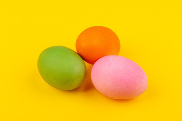 Colorful handmade Easter eggs. Top view of three eggs. Isolated on a yellow background. Preparing for Easter.